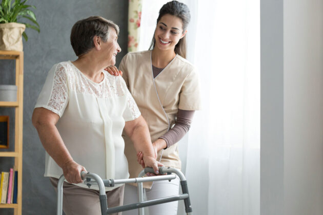 nurse helping older woman with physical therapy.